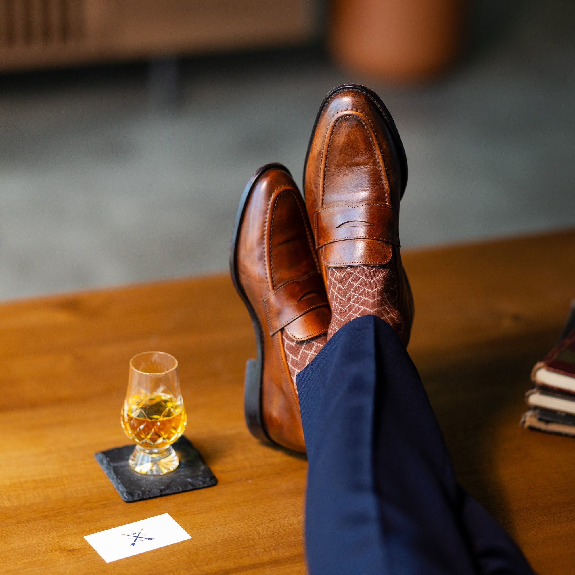 Close-up of brown patterned dress socks with navy trousers and brown penny loafers