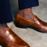Close-up of a Pecan and navy lattice dress sock above a brown leather loafer
