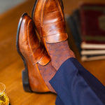 Close-up of brown dress socks with navy trousers and brown penny loafers