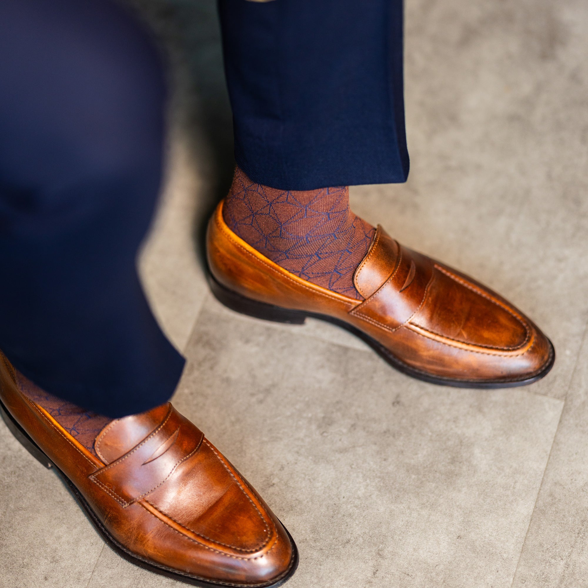 Brown patterned dress socks and penny loafers viewed from above