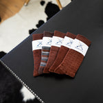 Five folded brown patterned dress socks from the Fall Brown Bundle on a black surface