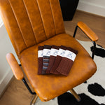 Overhead view of five folded brown dress socks on a caramel leather chair