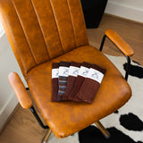 Overhead view of five folded brown dress socks on a caramel leather chair