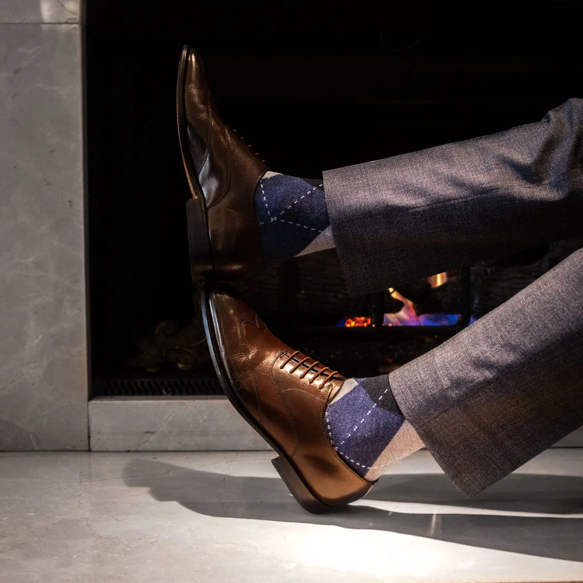Man wearing blue, charcoal, grey, and white argyle men's dress socks and gray slacks