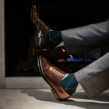 Man wearing green, charcoal, grey, and white argyle men's dress socks.