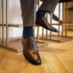 Man wearing midnight blue, solid, ribbed men's dress socks with brown shoes.