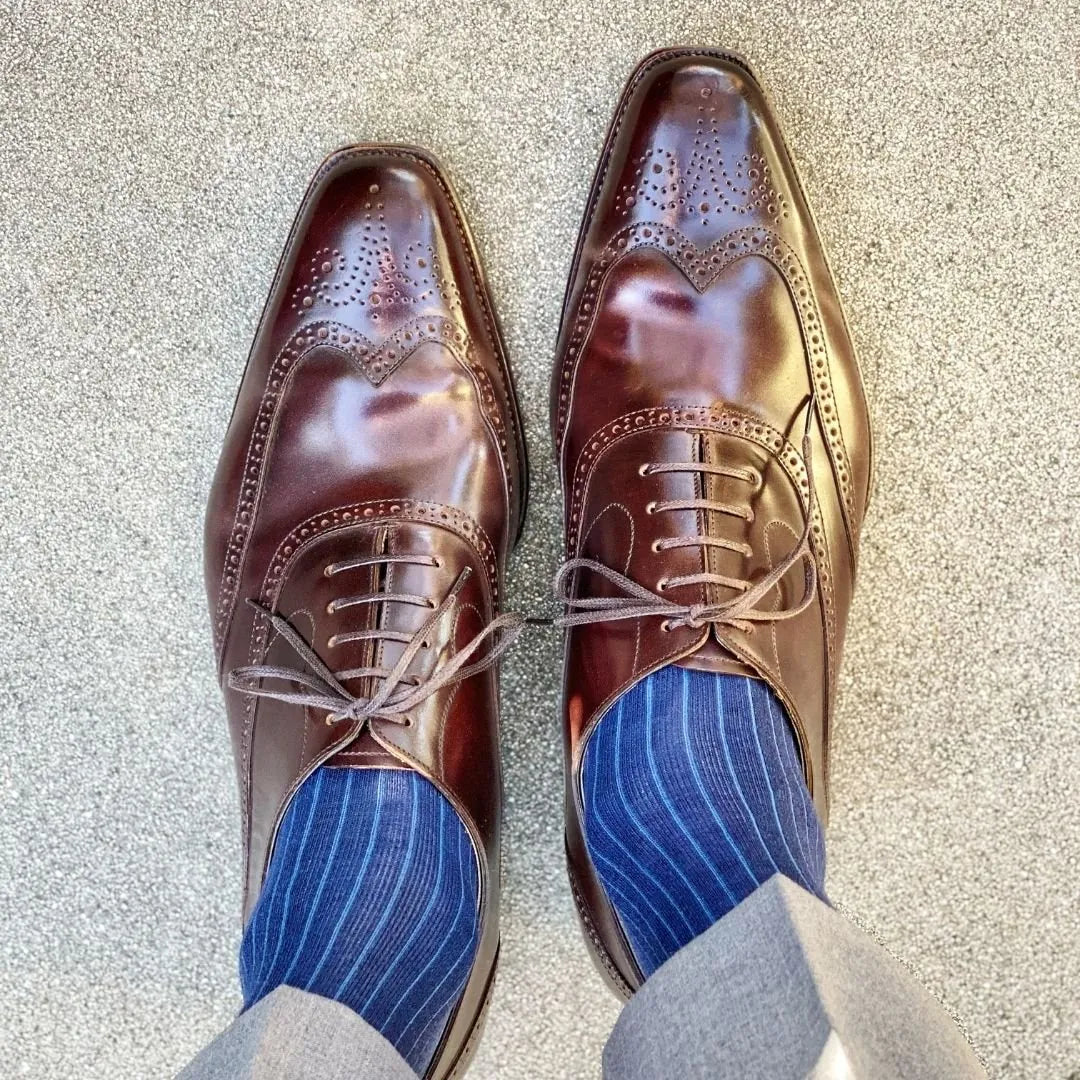 Man wearing midnight blue, solid, ribbed men's dress socks with brown shoes.