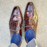 Man wearing midnight blue, solid, ribbed men's dress socks with brown shoes.