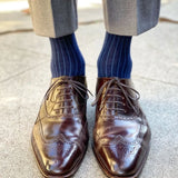 Man wearing midnight blue, solid, ribbed men's dress socks with brown shoes.