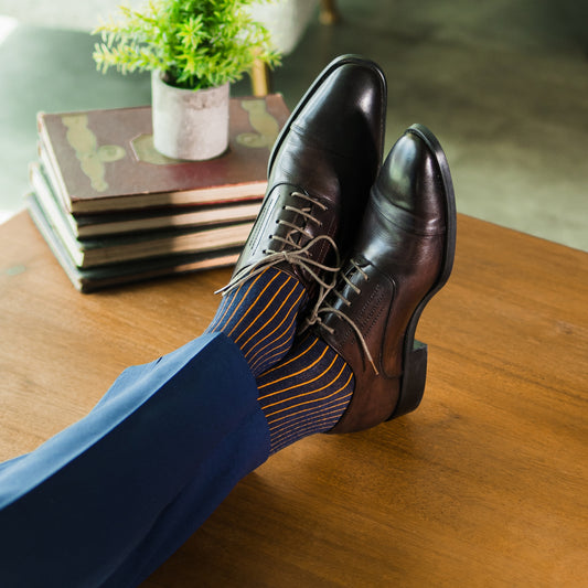 A navy men's dress sock with an orange ribbed pattern