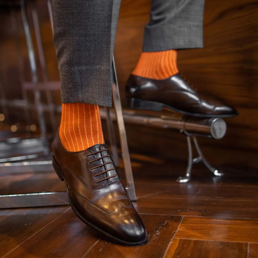 Man wearing orange, solid, tangerine ribbed men's dress socks.