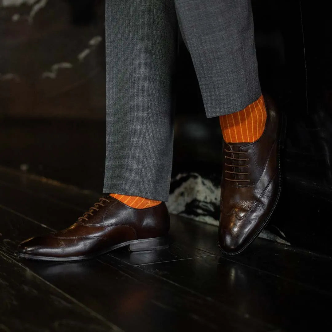 Man wearing orange, solid, tangerine ribbed men's dress socks.
