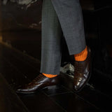 Man wearing orange, solid, tangerine ribbed men's dress socks.