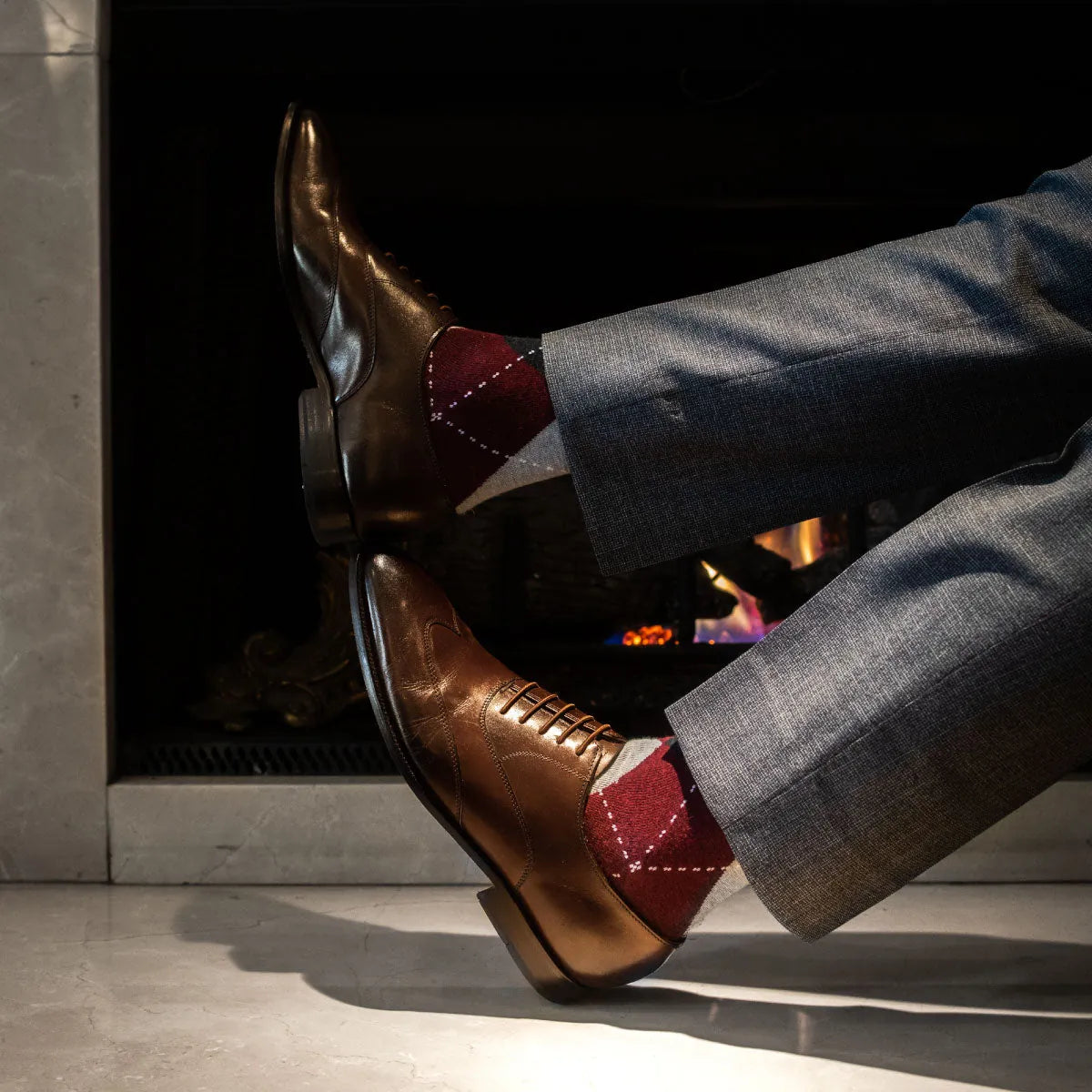 Man wearing red, charcoal, grey, and white argyle men's dress socks.
