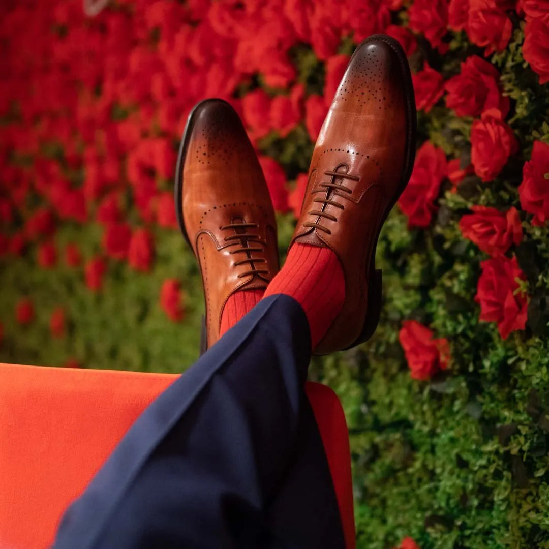 Man sitting with legs crossed wearing rose red ribbed men's dress socks.