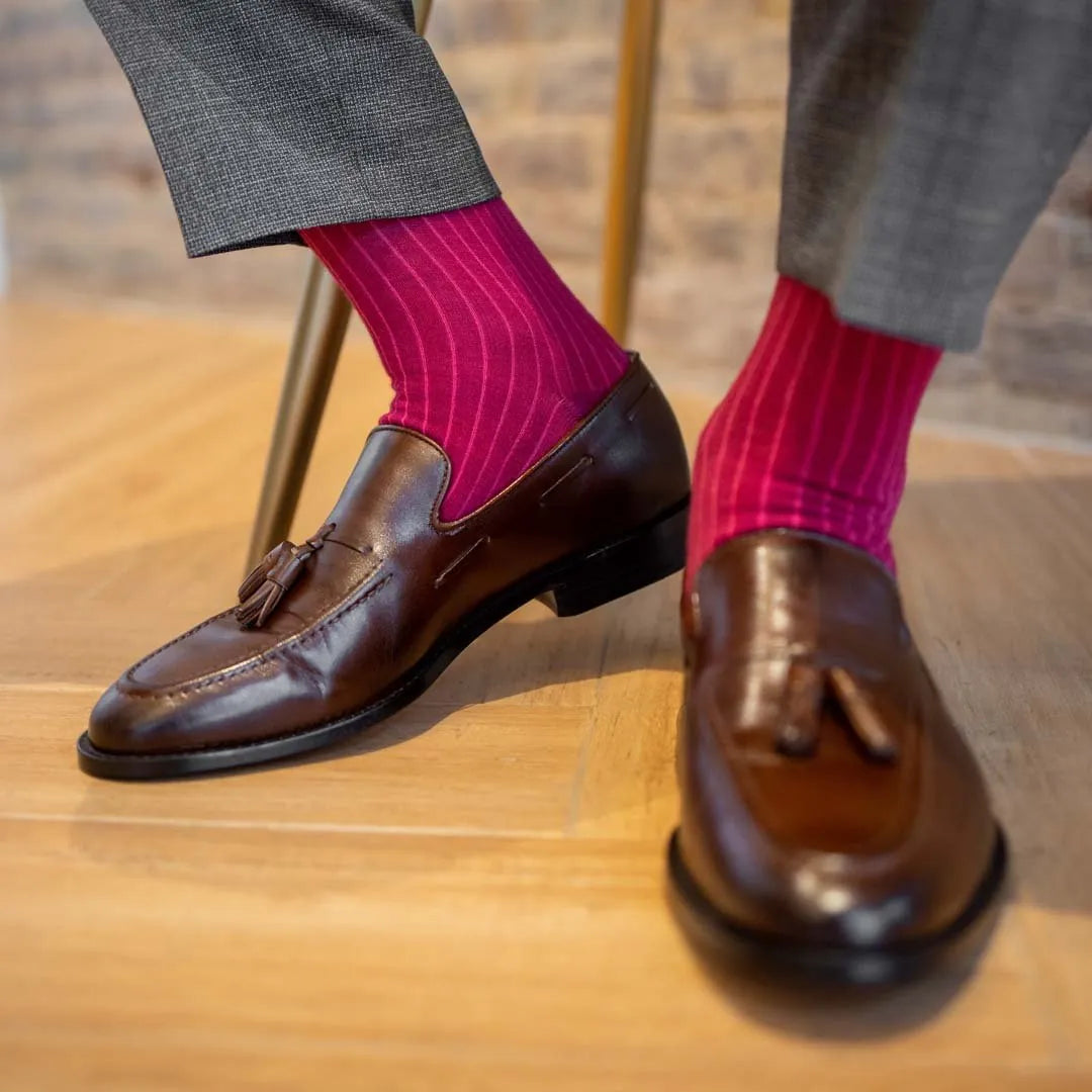 Man sitting wearing ruby, solid, magenta ribbed men's dress socks.