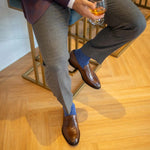 Man sitting wearing solid, blue, and navy blue ribbed men's dress socks and brown shoes.