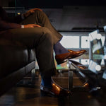 Man wearing solid, blue, and navy blue ribbed men's dress socks and brown shoes.