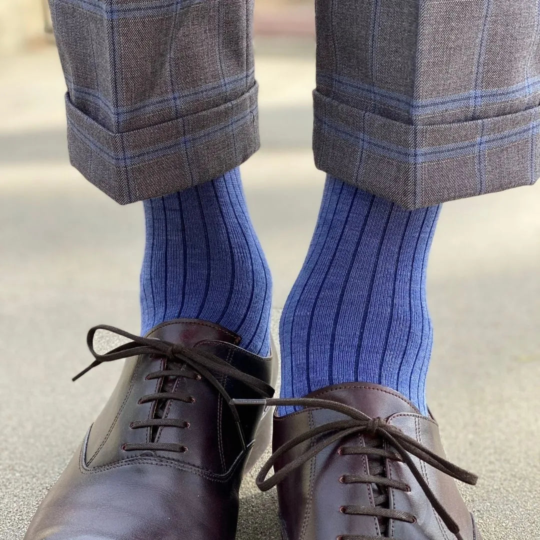 Man wearing solid, blue, and navy blue ribbed men's dress socks and shoes.