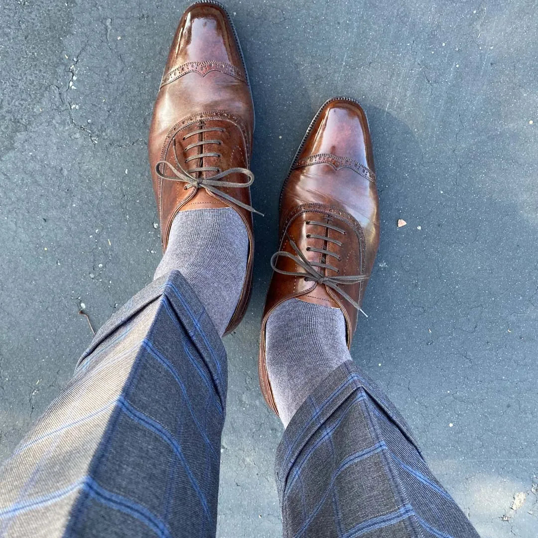 Man standing wearing steel gray men's dress socks, and brown shoes.