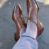 Man sitting down with legs crossed wearing steel gray men's dress socks and brown shoes.