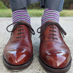 Man wearing purple, grey, and white striped dress socks and brown dress shoes