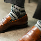 A cool men's dress sock combination of grey, sage, and olive stripes designed for refined versatility and subtle sophistication. 