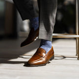 Man wearing heathered blue men's dress sock with ocean blue micro squares with grey slacks and brown shoes