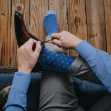 Man sitting wearing heathered blue and ocean blue micro-square socks