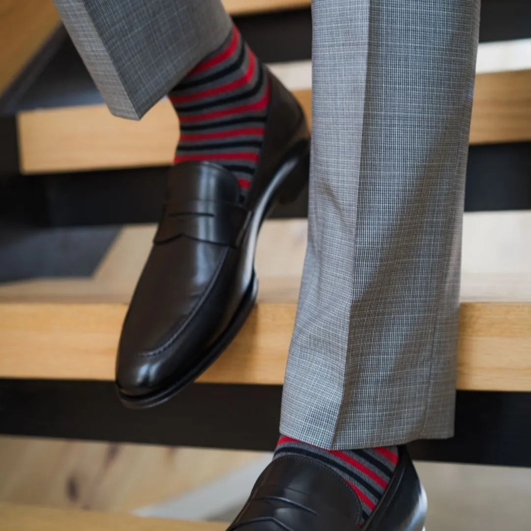 Man wearing charcoal grey, red, and black striped sock