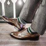 Man wearing green, taupe, and tan striped socks with dress shoes