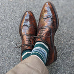Man wearing green, taupe, and tan striped socks with dress shoes