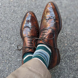 Man wearing green, taupe, and tan striped socks with dress shoes