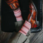 Man wearing coral, grey and white striped socks and dress shoes