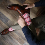 Man wearing coral, grey and white striped socks and dress shoes