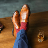 Red patterned sock worn with brown leather shoes and navy trousers