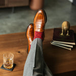 Red patterned sock worn with brown leather shoes and grey trousers