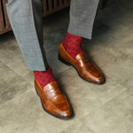 Red patterned sock worn with brown leather shoes and gray trousers