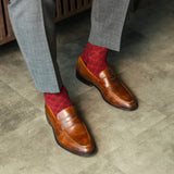Red patterned sock worn with brown leather shoes and gray trousers