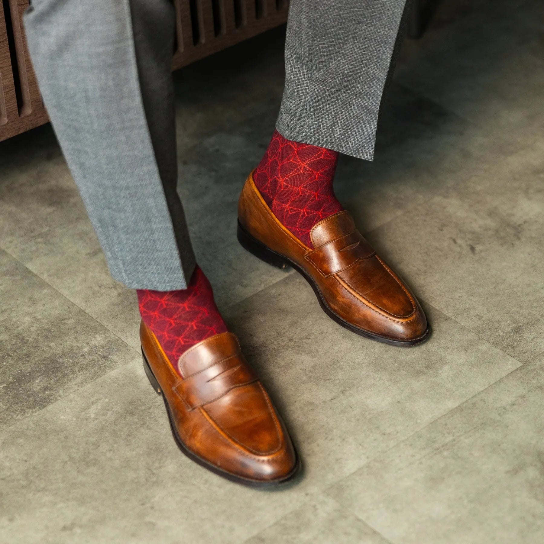 Red patterned sock worn with brown leather shoes and gray trousers