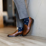 Man wearing grey pants, navy blue socks with white polka dots, and brown dress shoes.
