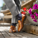 Man wearing grey pants, navy blue socks with white polka dots, and brown dress shoes.