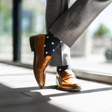 Man wearing grey pants, navy blue socks with white polka dots, and brown dress shoes.