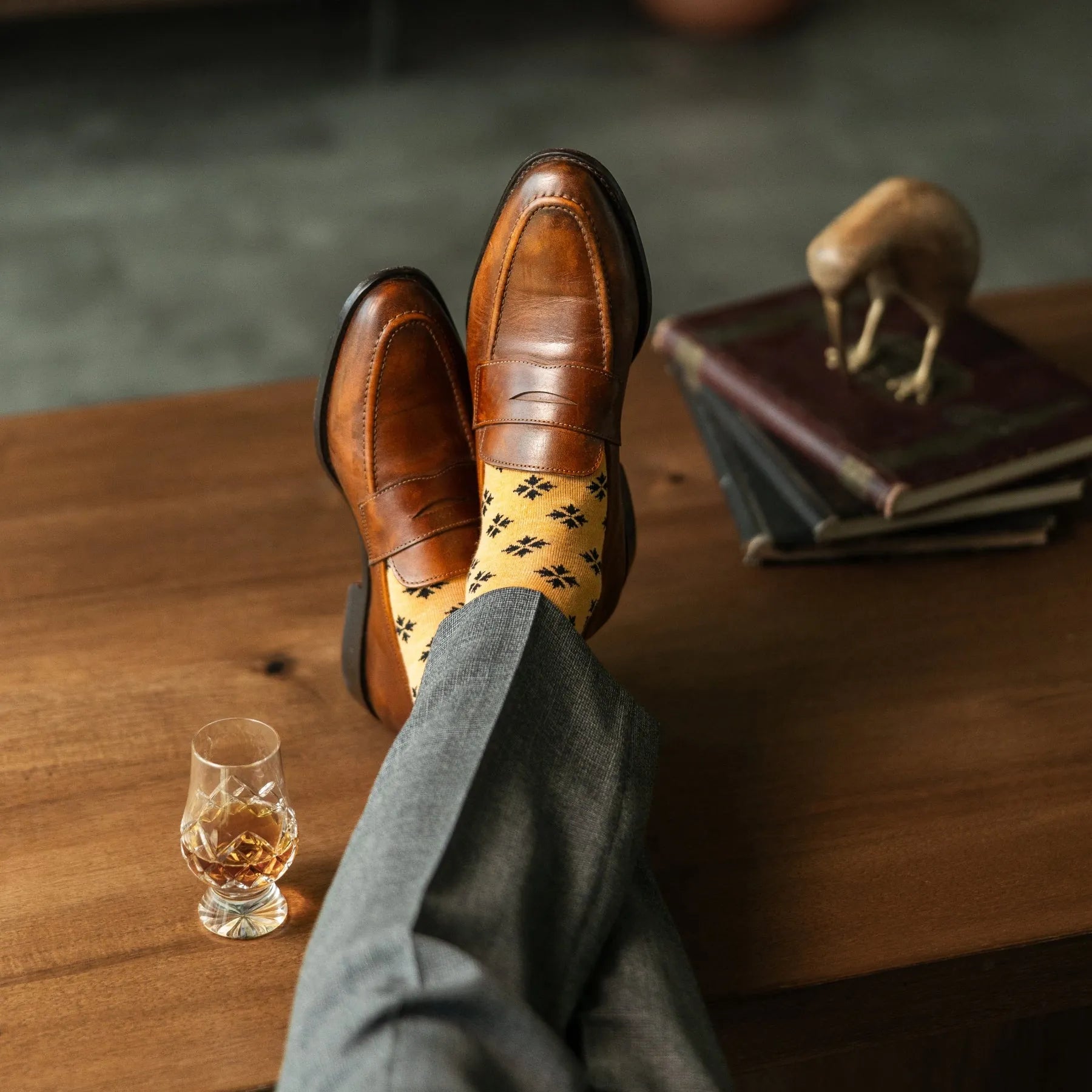 A light rust-orange men's dress sock with a bold black leaf motif