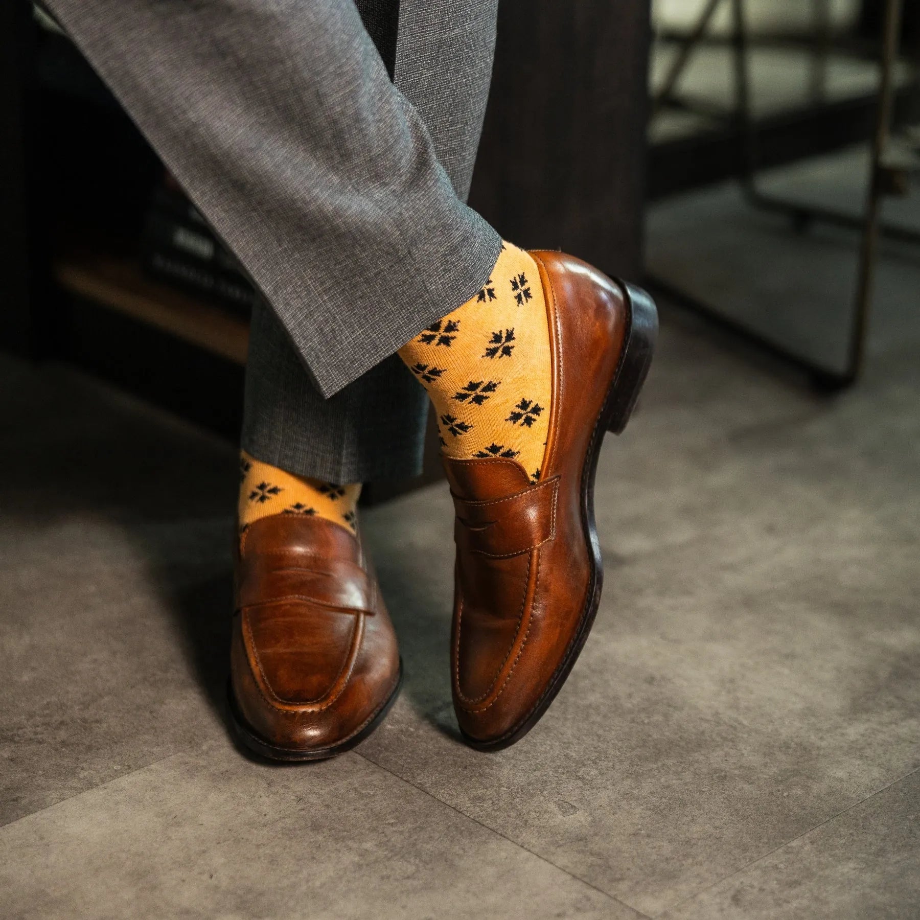 A light rust-orange men's dress sock with a bold black leaf motif