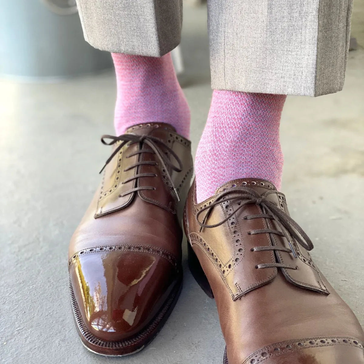 Man wearing light grey slacks, pink socks, and brown shoes.