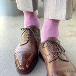 Man wearing light grey slacks, pink socks, and brown shoes.