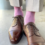 Man wearing light grey slacks, pink socks, and brown shoes.