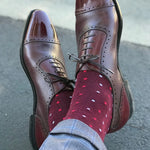 Man wearing cranberry socks with red and powder blue micro-squares