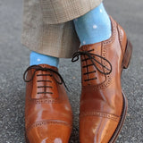 Man wearing baby blue and white polka dot socks, and dress shoes.